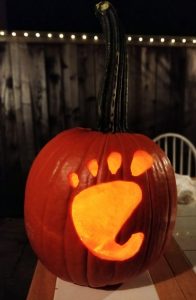 A jack-o-lantern: an orange pumpkin with a GNOME foot carved into it and candle light coming through the foot.