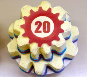 A cake shaped like two gears with a red "20" printed on it.