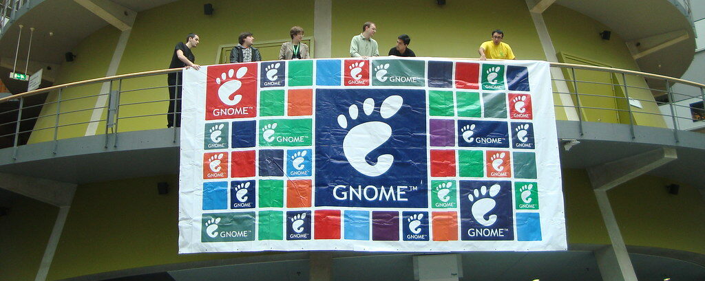 A GNOME banner hung on a tower, with several people behind it.