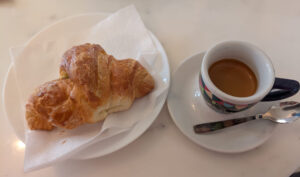 A brioche and espresso cup sit on a table