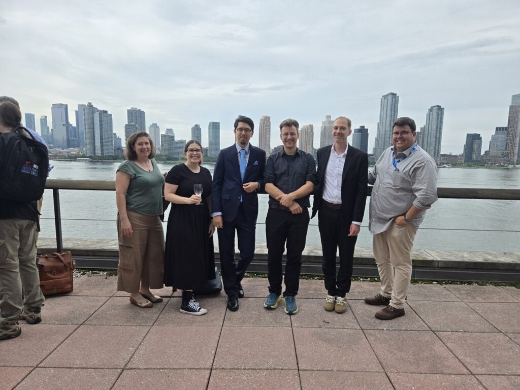 Six people in front of a river on a building