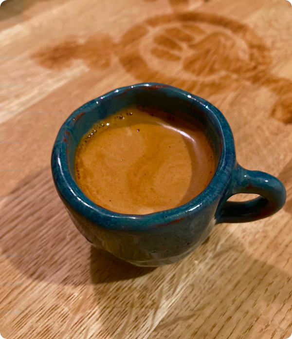 Petrol espresso cup with espresso on wooden board